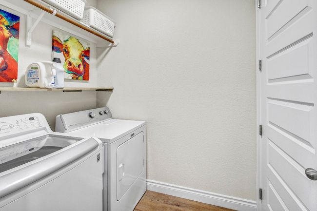Laundry area with washing machine and dryer and light wood-style flooring | Image 36