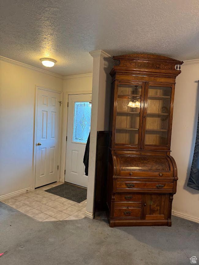Carpeted entrance foyer featuring a textured ceiling, ornamental molding, and baseboards | Image 19