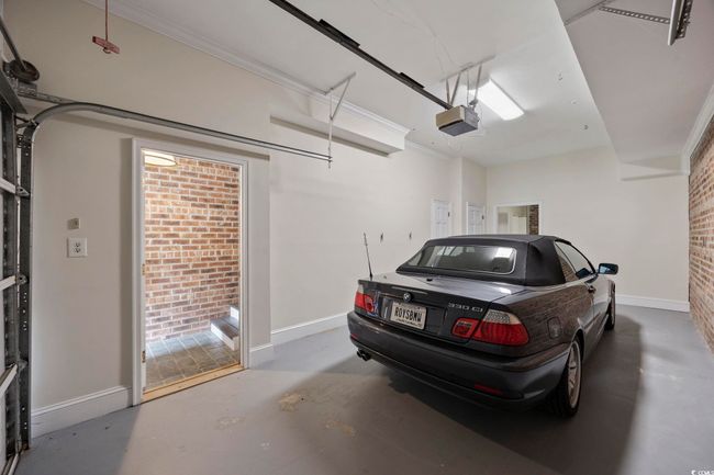 Garage featuring a garage door opener and baseboards | Image 35
