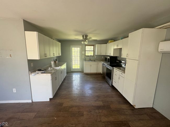kitchen featuring white cabinets, a sink, ceiling fan, stainless steel appliances, and dark wood-style flooring | Image 8