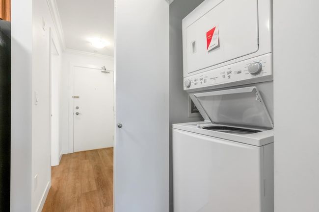 Washroom with stacked washer / drying machine, light wood finished floors, and ornamental molding | Image 21