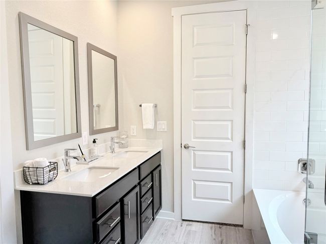 Full bathroom featuring double vanity, shower / washtub combination, wood finished floors, and a sink | Image 21