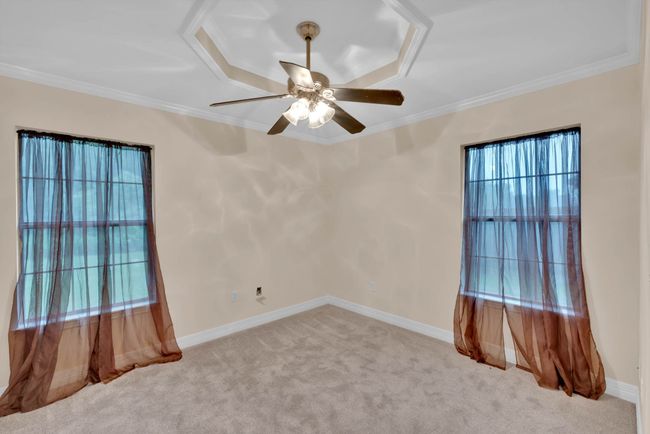 Carpeted spare room with plenty of natural light, crown molding, ceiling fan, and a raised ceiling | Image 25