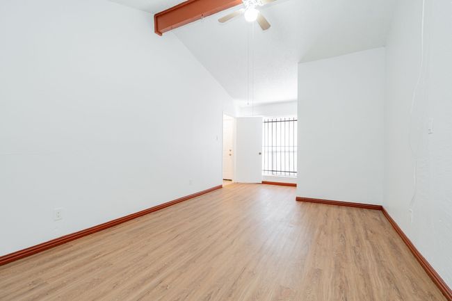 Spare room featuring light wood finished floors, baseboards, beamed ceiling, a ceiling fan, and high vaulted ceiling | Image 19