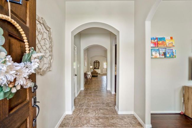 Step inside your future home and notice the arched opening to the right, welcoming you into a versatile space. Straight ahead, elegant arched doorways lead into the open living room and kitchen. | Image 4