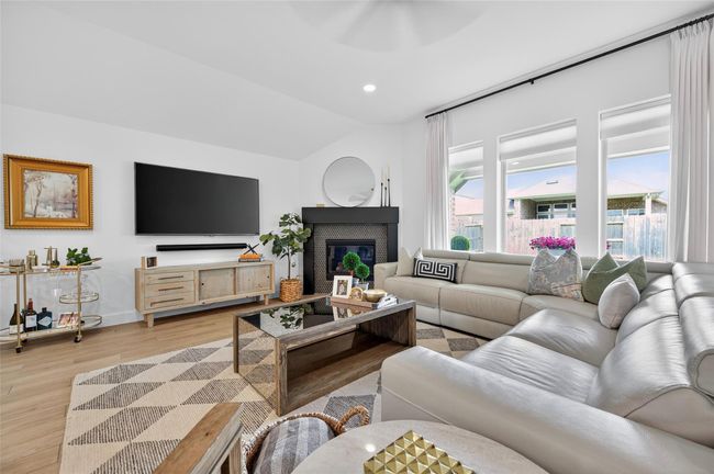 Bright living space featuring a modern fireplace and a trio of large windows offering abundant natural light. The open layout and clean lines enhance the room’s airy, comfortable feel. | Image 7