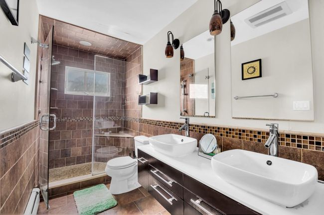 Bathroom featuring tile walls, visible vents, a sink, and a baseboard heating unit | Image 16