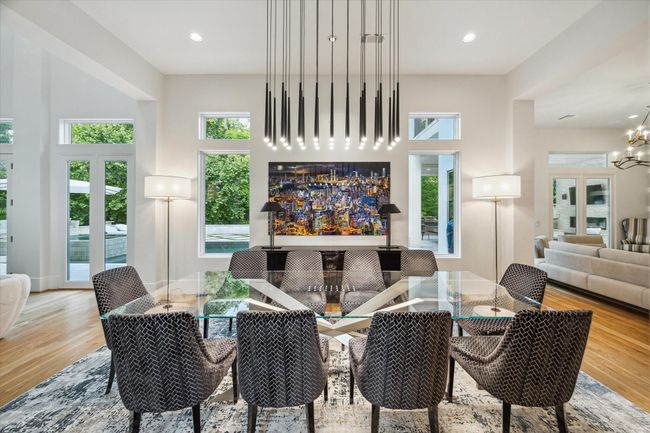 This luxurious dining room features expansive windows that flood the space with natural light, highlighting the high ceilings. | Image 10