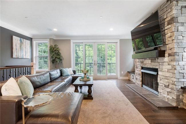 Main floor Living Room has hardwood floor, gas fireplace with stone surround and sliding doors to a balcony. | Image 4
