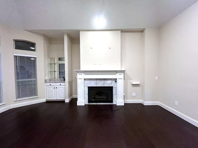 Unfurnished living room featuring a fireplace and dark wood-type flooring | Image 19
