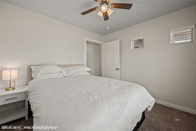 Bedroom with dark colored carpet, baseboards, and ceiling fan | Image 15