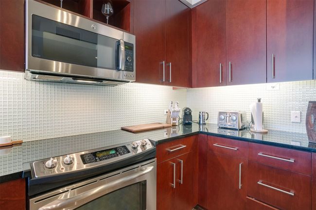 Kitchen featuring appliances with stainless steel finishes, tasteful backsplash, dark brown cabinets, and dark stone countertops | Image 13