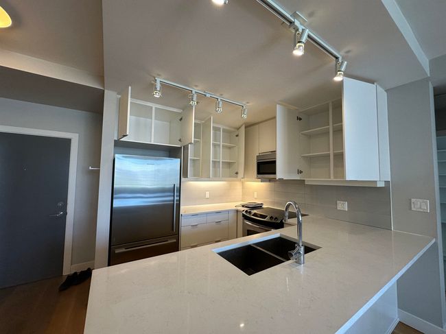Kitchen with open shelves, stainless steel appliances, a sink, and track lighting | Image 19