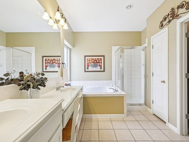 Bathroom with a shower stall, double vanity, tile patterned flooring, a bath, and a chandelier | Image 20