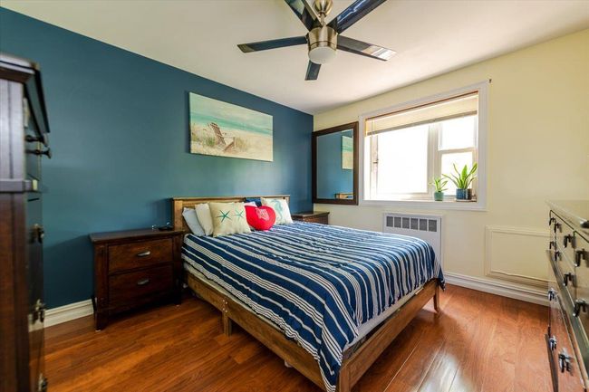 Bedroom with wood finished floors, ceiling fan, and radiator heating unit | Image 13