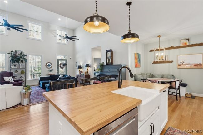 Kitchen with a sink, wood counters, stainless steel dishwasher, ceiling fan with notable chandelier, and open floor plan | Image 11