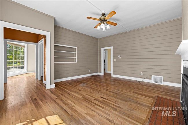 Unfurnished living room featuring wood-type flooring, wood walls, and a ceiling fan | Image 22