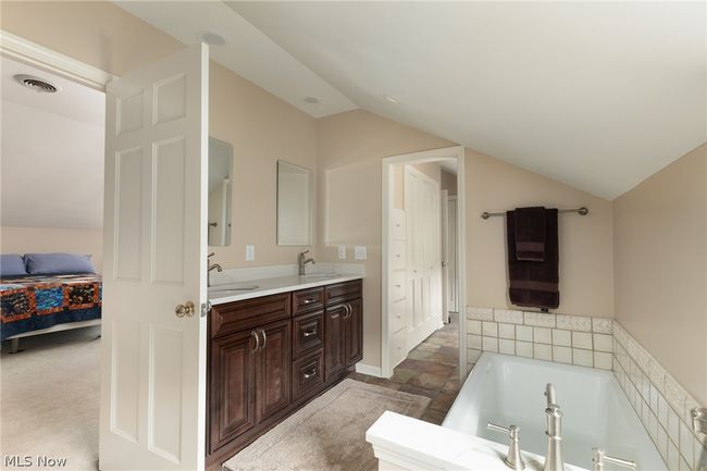 Bathroom featuring vaulted ceiling, a bathing tub, dual sinks, and large vanity | Image 41