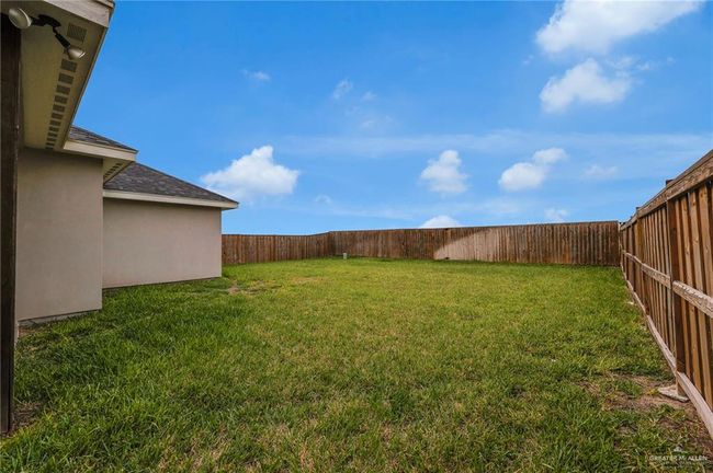 Rear view of property featuring stucco siding, roof with shingles, a yard, and a fenced backyard | Image 18