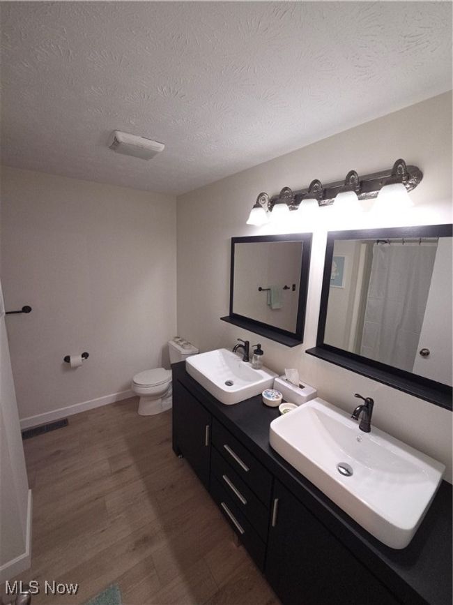 Bathroom with a sink, toilet, wood finished floors, and a textured ceiling | Image 26