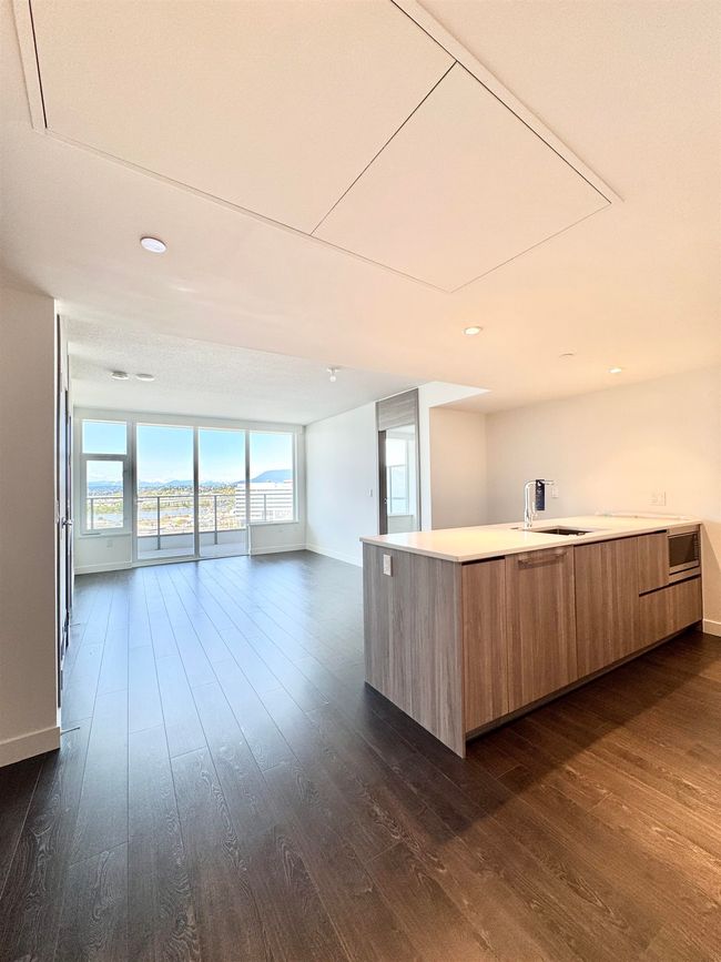 Kitchen with light countertops, modern cabinets, baseboards, open floor plan, and dark wood-style flooring | Image 5