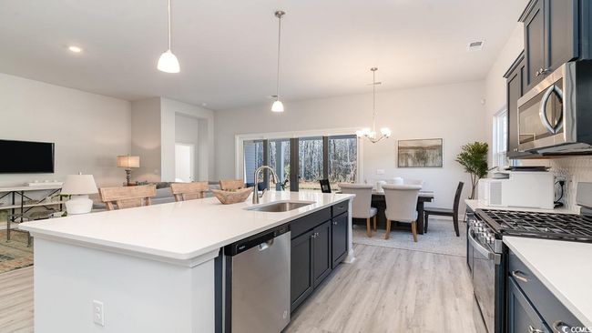 Kitchen featuring tasteful backsplash, light wood-type flooring, stainless steel appliances, an island with sink, and sink | Image 17
