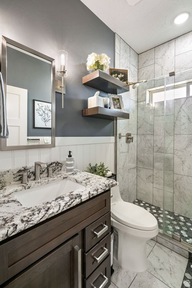 Full bath featuring vanity, a shower stall, marble finish flooring, and wainscoting | Image 52