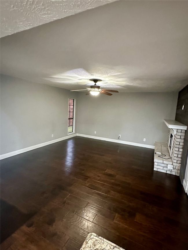 second living area with ceiling fan, dark wood-type flooring, a brick fireplace, and a textured ceiling | Image 16