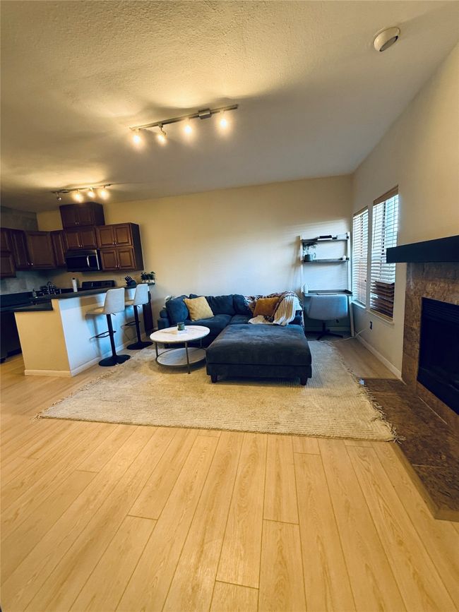 Living room featuring light wood-style floors, a textured ceiling, and a tiled fireplace | Image 26