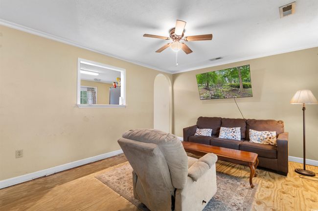Living room with ornamental molding, arched walkways, and a ceiling fan | Image 14