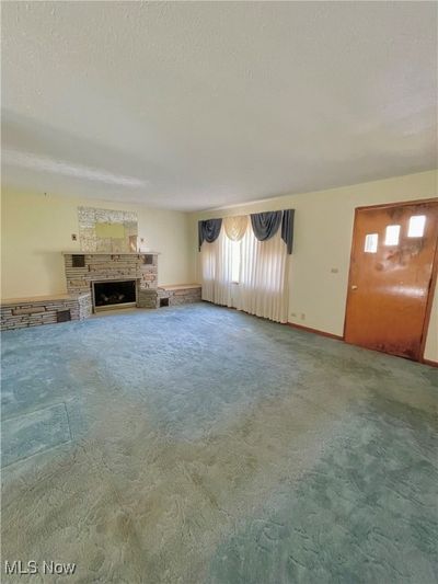 Unfurnished living room with a textured ceiling and carpet flooring | Image 2