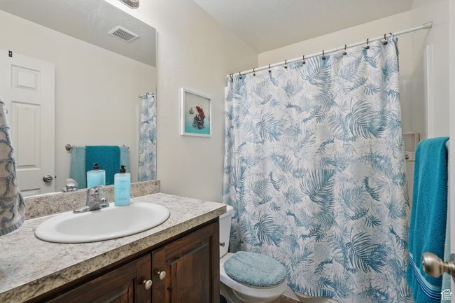 Bathroom with toilet, curtained shower, vanity, and visible vents | Image 26
