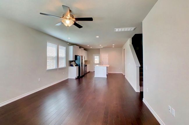 Unfurnished living room with visible vents, baseboards, ceiling fan, a sink, and dark wood-style floors | Image 6