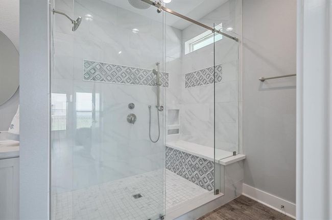 The primary bathroom boasts a large shower with a seat and a rain shower head | Image 35