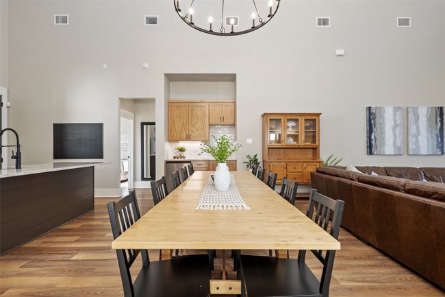 Dining area with a high ceiling, a chandelier, light wood finished floors, and baseboards | Image 6