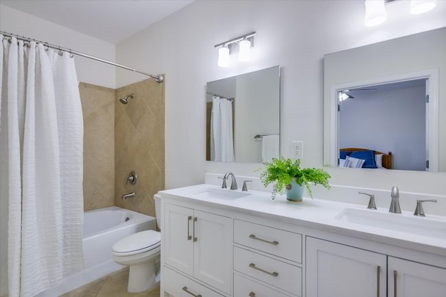 Bathroom featuring shower / tub combo with curtain, double vanity, and tile patterned floors | Image 10