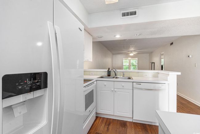 Kitchen with white appliances, a sink, a peninsula, and dark wood-type flooring | Image 21