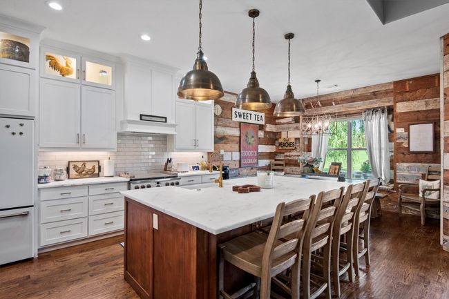 Kitchen featuring freestanding refrigerator, white cabinetry, a kitchen island, pendant lighting, and tasteful backsplash | Image 11