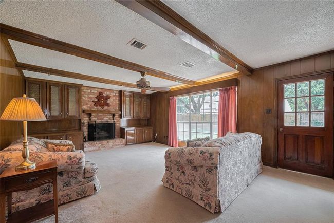 Spacious family room featuring a cozy gaslog fireplace and traditional wooden beam accents. | Image 13