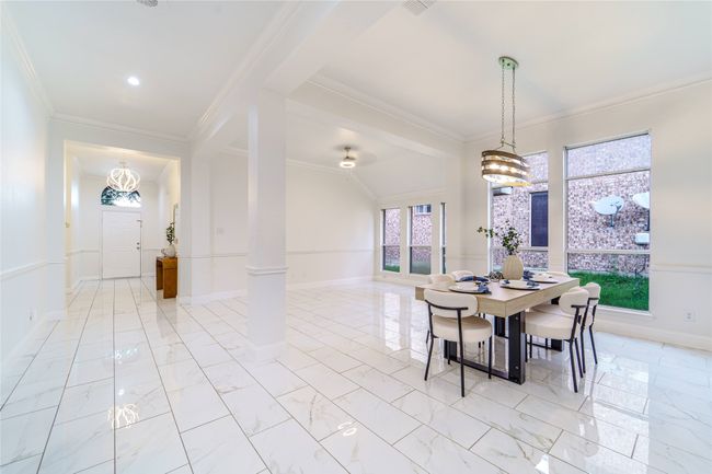 Dining room featuring ornamental molding, decorative columns, light marble finish flooring, and a chandelier | Image 8