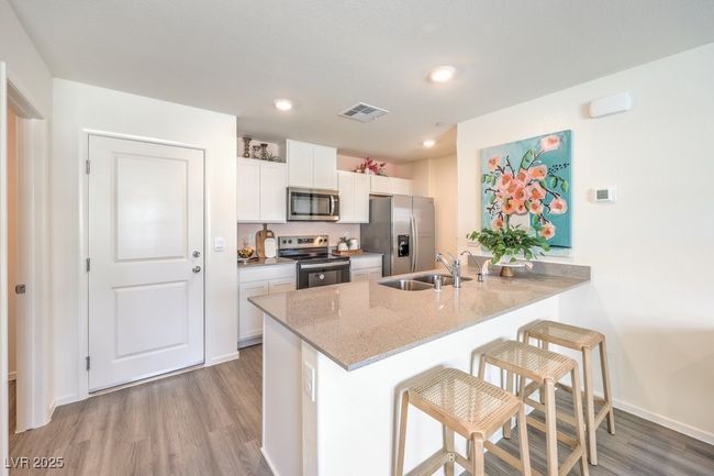Kitchen with a sink, light wood-type flooring, visible vents, a peninsula, and appliances with stainless steel finishes | Image 12