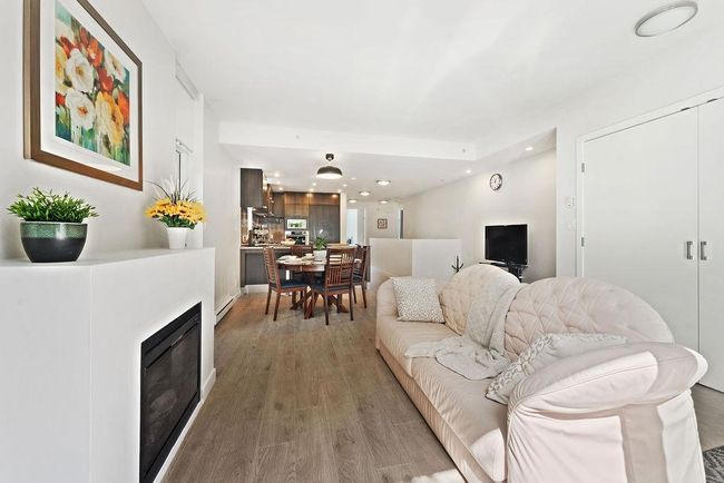 Living area featuring a glass covered fireplace, recessed lighting, baseboard heating, and light wood-type flooring | Image 15