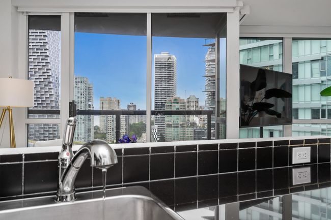 Kitchen with tasteful backsplash, stainless steel appliances, dark countertops, white cabinetry, and light wood-type flooring | Image 12