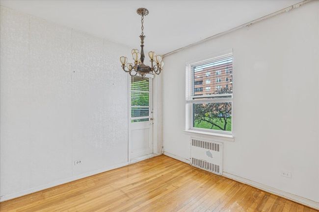 Empty room featuring radiator, a chandelier, and hardwood / wood-style floors | Image 6