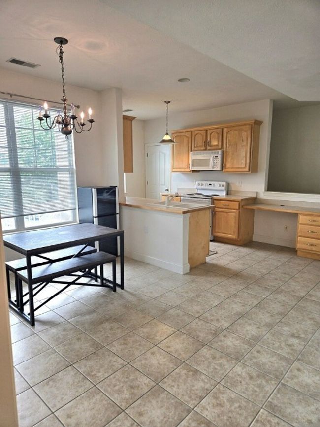 The eating area is spacious and bright, with a large window and chandelier. | Image 5
