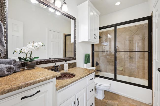 Full bath with vanity, toilet, bath / shower combo with glass door, stone finish flooring, and recessed lighting | Image 22