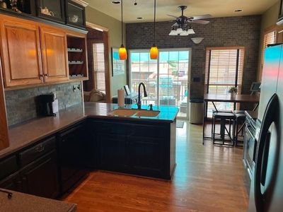 Kitchen featuring pendant lighting, stainless steel fridge, sink, kitchen peninsula, and wood-type flooring | Image 3