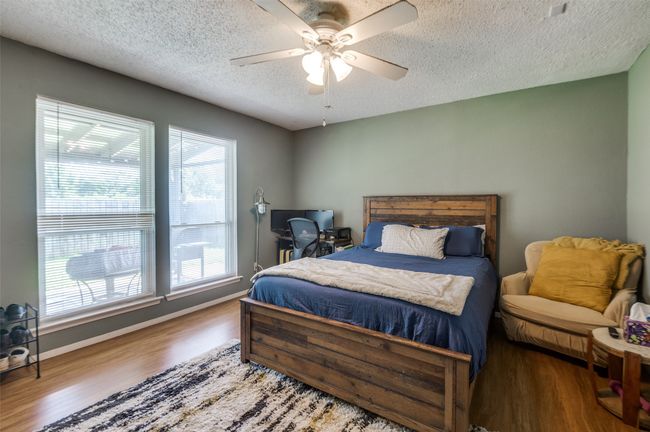 Bedroom featuring wood finished floors, a textured ceiling, a desk, and a ceiling fan | Image 20