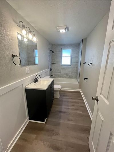 Full bathroom with wood-type flooring, vanity, a textured ceiling, toilet, and tiled shower / bath | Image 3