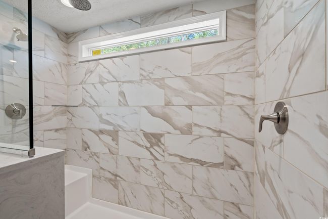 Bathroom featuring a textured ceiling, tiled shower, and plenty of natural light | Image 19